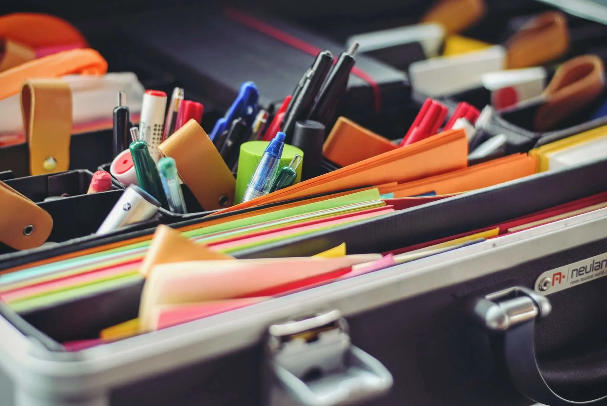 stationery organizer with colorful papers, pens, and accessories in a sleek metallic case, colorful office supplies neatly arranged