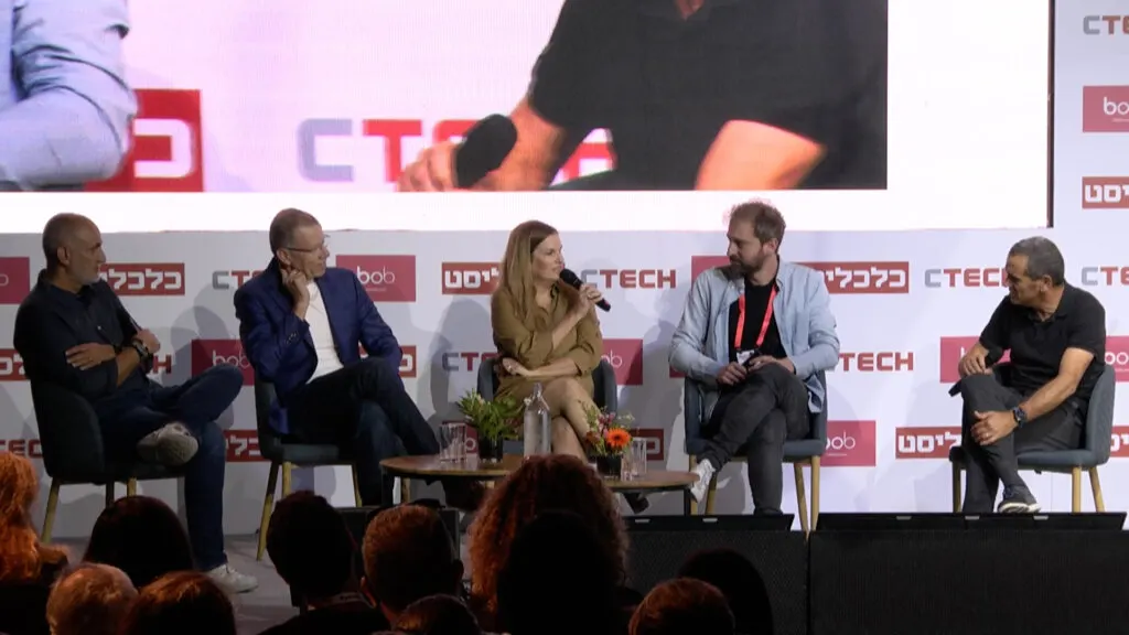 panel discussion, CTECH event with speakers discussing insights, surrounded by an audience and branding displays