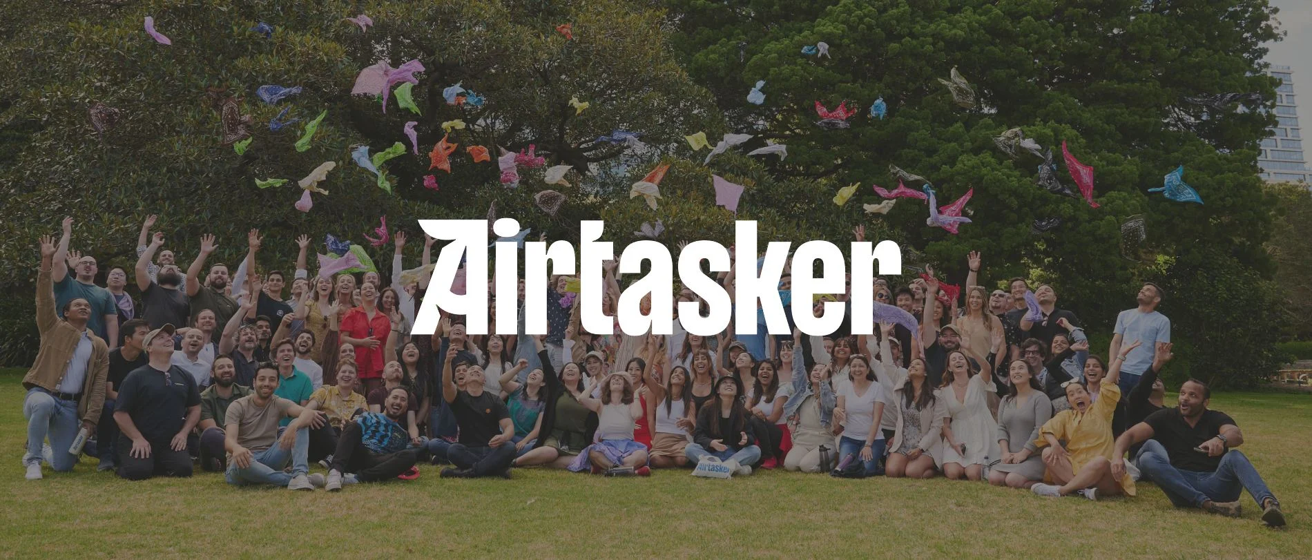 Airtasker team celebrating outdoors, throwing colorful fabric above them in a joyful group photo., Airtasker group photo, Celebration outdoors