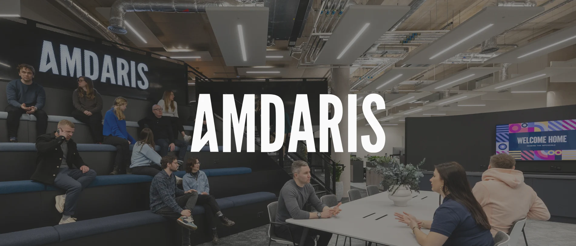 Amdaris office space featuring modern seating, collaborative areas, and vibrant digital signage with a welcoming message., Modern office design with Amdaris brand display and collaborative workspace for team interaction.