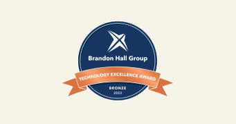 Brandon Hall Group Technology Excellence Award bronze emblem for 2023, Circular badge featuring navy blue with bronze ribbon.