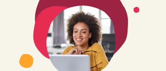 woman with curly hair smiling at laptop, wearing yellow sweater, in bright office setting with colorful shapes, happy remote work environment