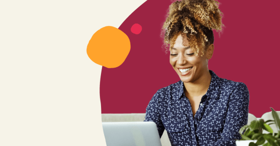 smiling woman in a blue patterned shirt working on a laptop with a green plant and colorful background, happy woman engaged in technology