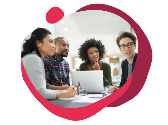 collaborative team meeting with diverse professionals focused on a laptop, engaged discussion around a table with documents