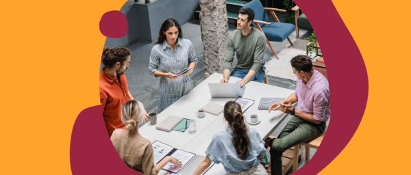 collaborative team meeting around a table with laptops, discussing ideas in a modern office space, diverse group brainstorming with digital devices