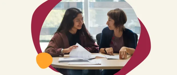 young woman and older woman discussing over documents at a table, engaged in collaborative conversation, two women interacting with papers in a bright setting