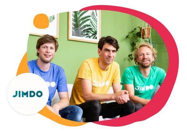 JIMDO team members in colorful shirts, posing against a green background with plants and framed artworks., JIMDO, team_photo