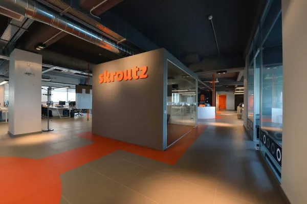 skroutz-office-reception-modern-design-colorful-elements, woman-entering-glass-enclosed-space-comfortable-seating
