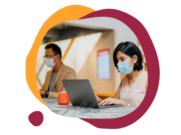 working professionals in masks using laptops in a modern workspace with orange and maroon abstract shapes, office environment with a casual feel and focus on productivity