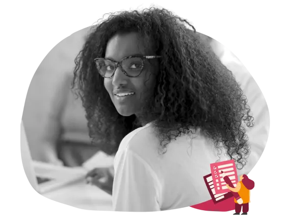 smiling woman with curly hair and glasses looking back at laptop, creative workspace setting with digital elements