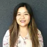 cheerful woman with long hair in floral blouse against grey background, portrait emphasizing friendly facial expression and style
