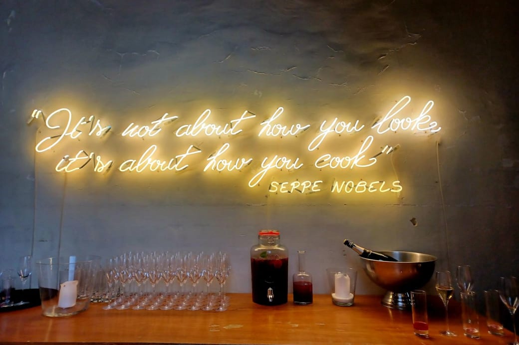 Tekst in neon tegen een muur: “It's not about how you look, it's about how you cook” signed Seppe Nobels