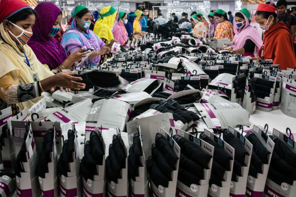 Textielarbeidsters in Bangladesh staan aan en tafel met verpakte nylonkousen.