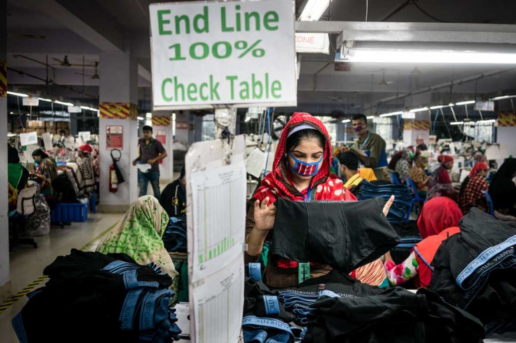 Een textielarbeidster in een kledingfabriek in Dhaka houdt een boxershort in de handen.