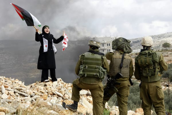 Een Palestijnse vrouw protesteert in 2009 voor Israëlische soldaten tegen de belegering van Gaza. De militaire controle-infrastructuur in de Palestijnse gebieden is niet tijdelijk, ze is een permanent schild.