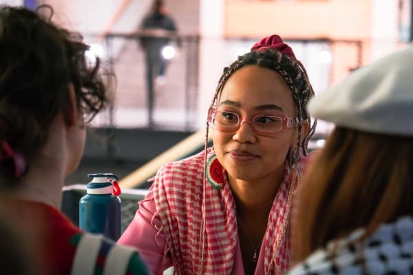 Influencer en klimaatactiviste Mikaela Loach kijkt naar haar gesprekspartners recht tegenover zich, net naast de lens.