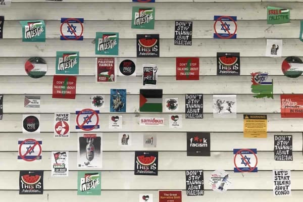 Beeld van flyers met onder andere 'Free Palestine'-boodschappen op een rolluik.
