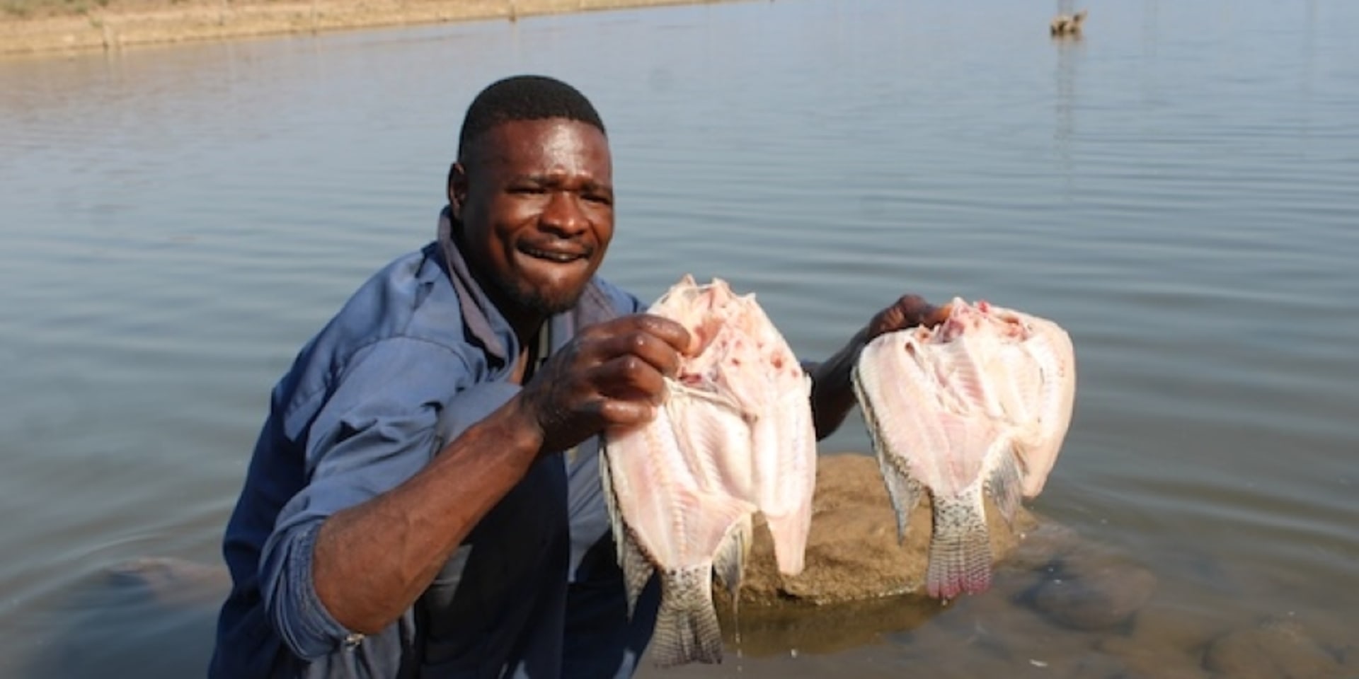 Visser Godknows Skota maakt vis schoon aan de rand van het Kariba-meer in Zimbabwe.