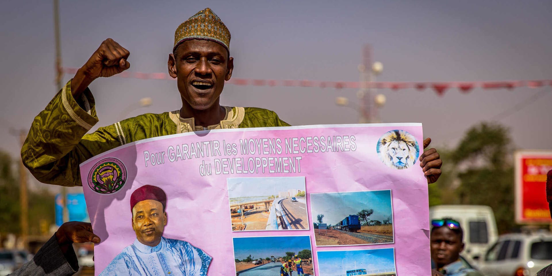 Een aanhanger van huidig president Issoufou Mahamadou poseert met zijn affiche, dat de nodige middelen voor ontwikkeling belooft.