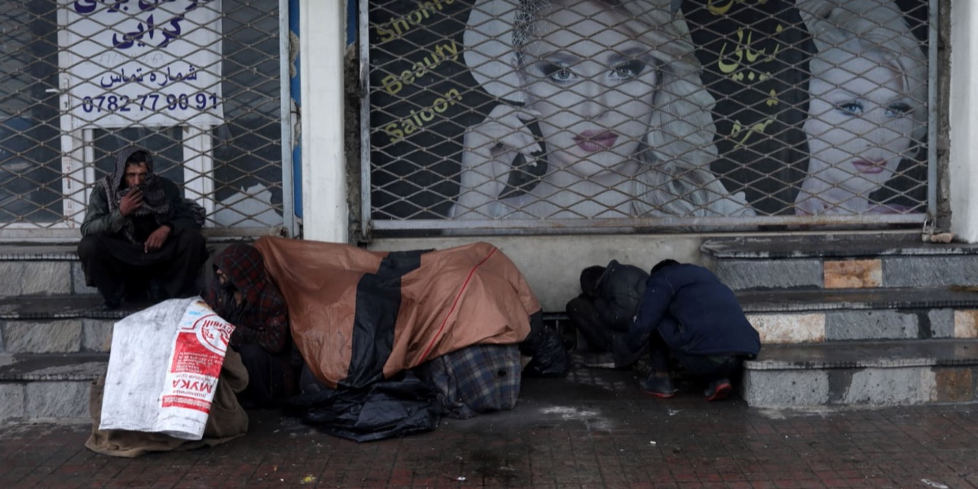 Januari 2022, mensen zitten voor een gesloten schoonheidssalon in de Afghaanse hoofdstad Kaboel.