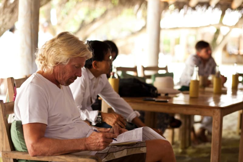 richard branson reading with a pen 
