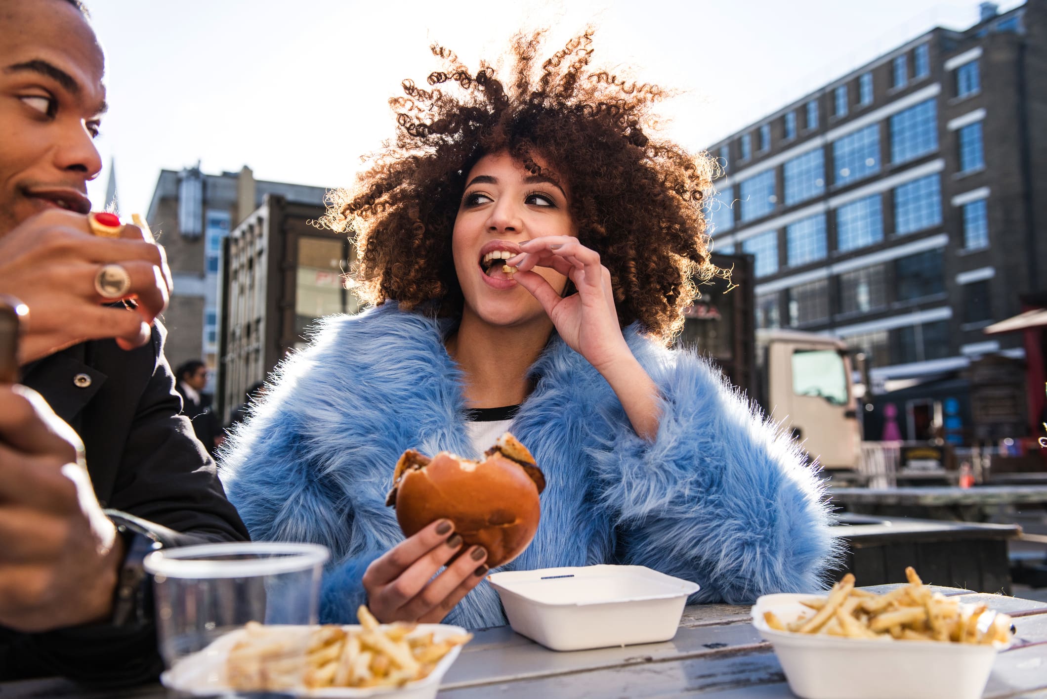 Two people smile while eating chips and burgers Two people smile while eating chips and burgers