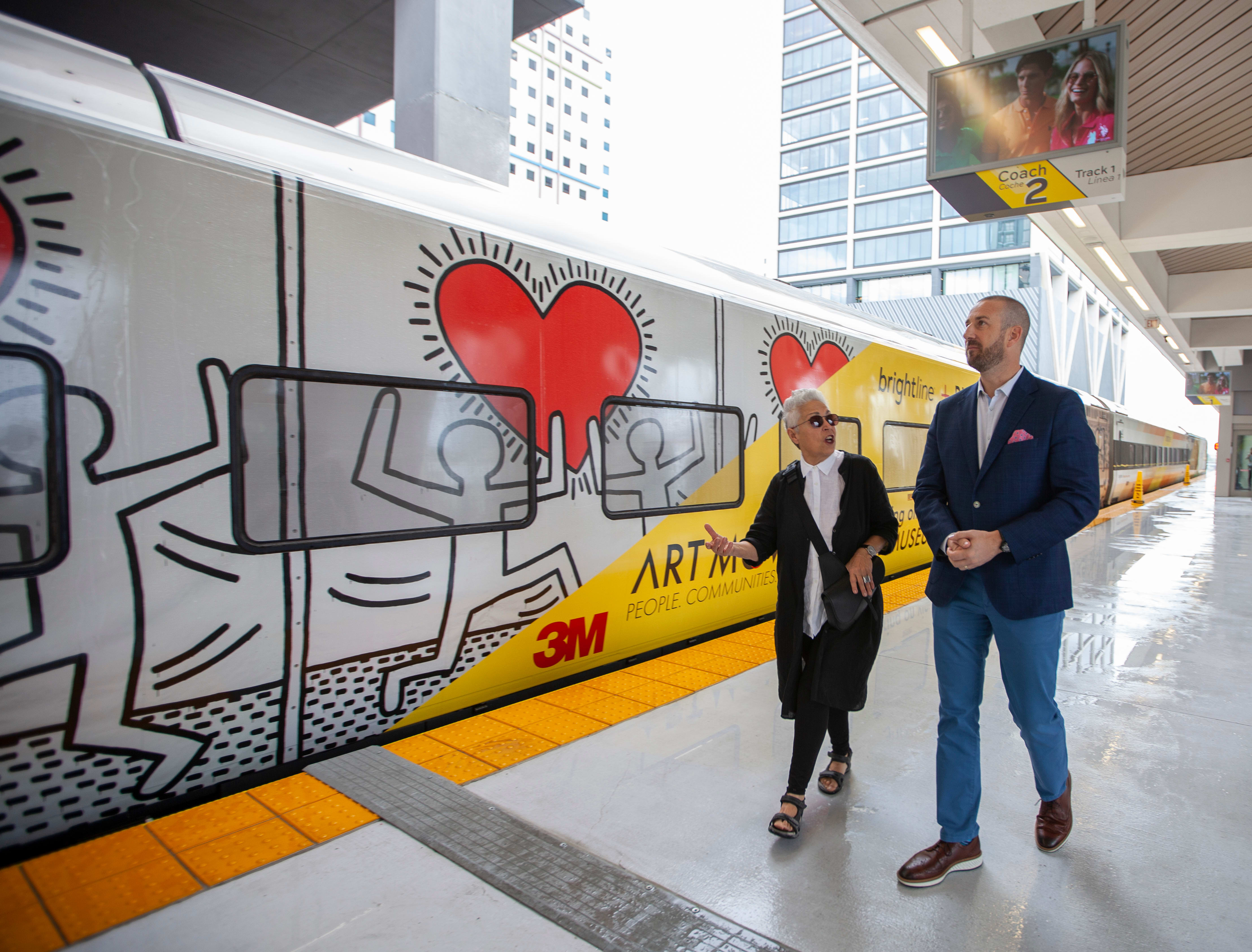 Brightline president Patrick Goddard and Mera Rubell in front of the Keith Haring train Brightline president Patrick Goddard and Mera Rubell in front of the Keith Haring train