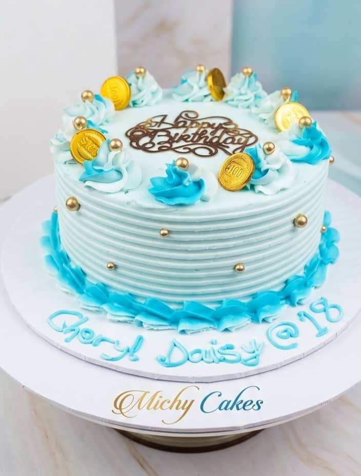 Pale blue buttercream birthday cake with blue flowers and gold accents