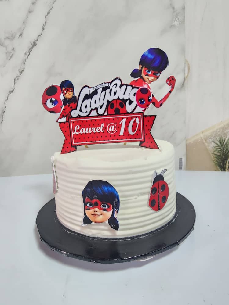 White Ladybug-themed birthday cake with red and blue toppers