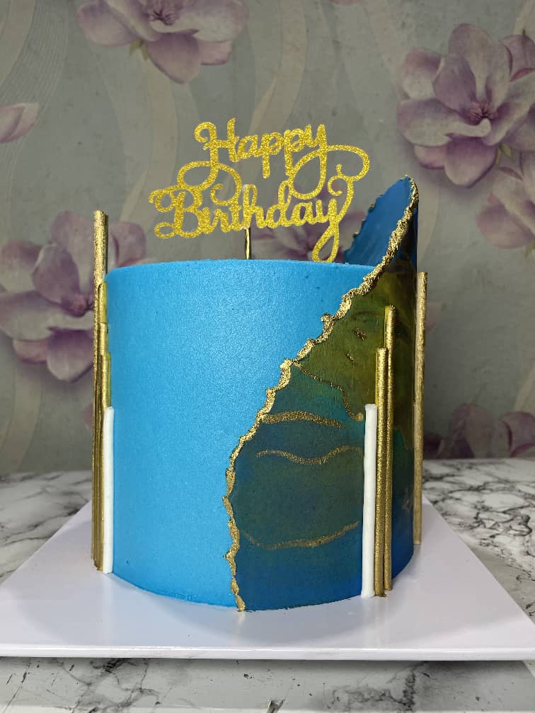 Blue cake with a gold-edged agate panel, gold and white sticks and a gold happy birthday topper