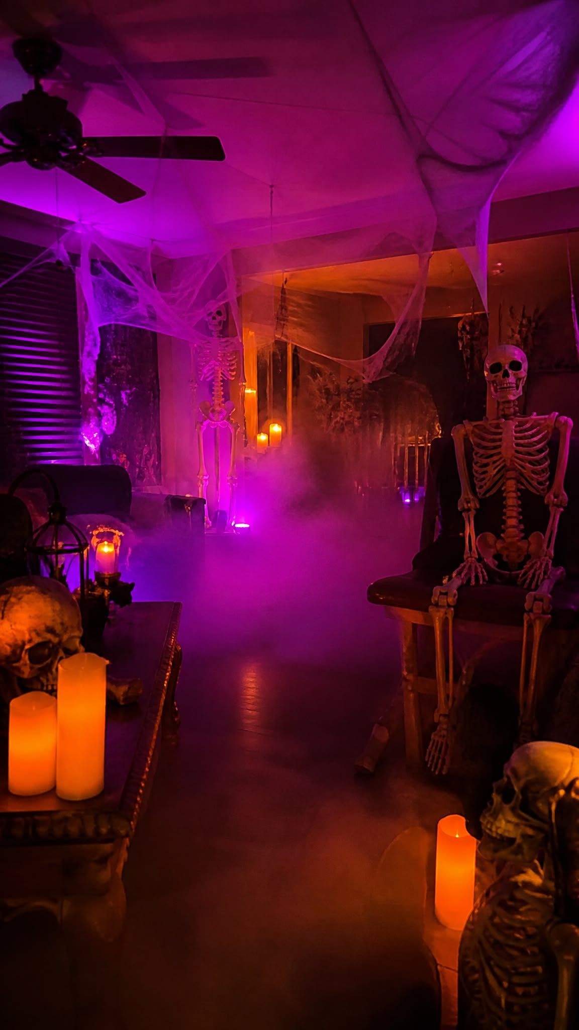 Room lit in purple and orange for a Halloween party with glowing pumpkins and hanging decorations