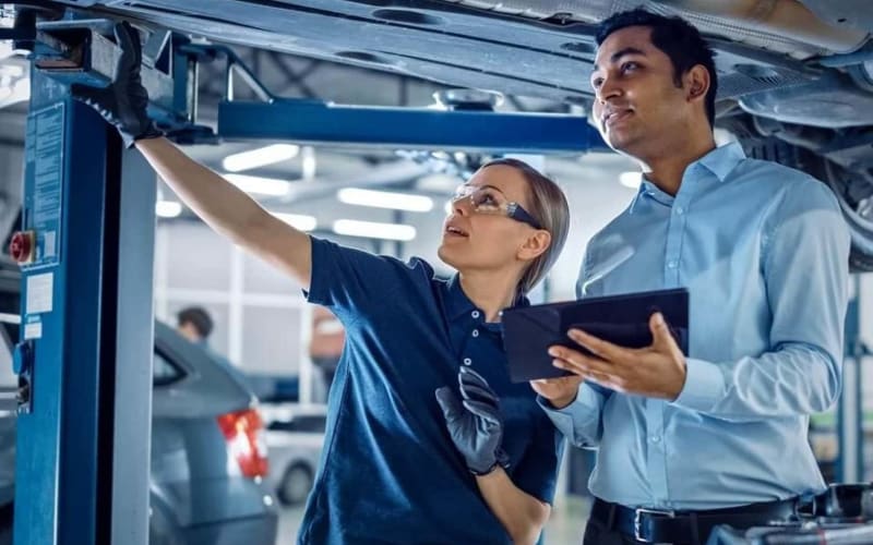 Two technicians working beneath a vehicle on a lift