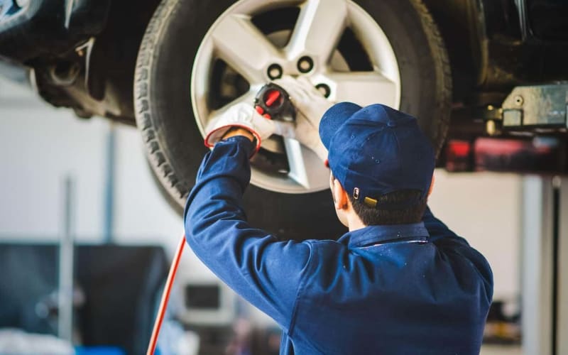 Technician tightening a wheel with an impact wrench during tire service