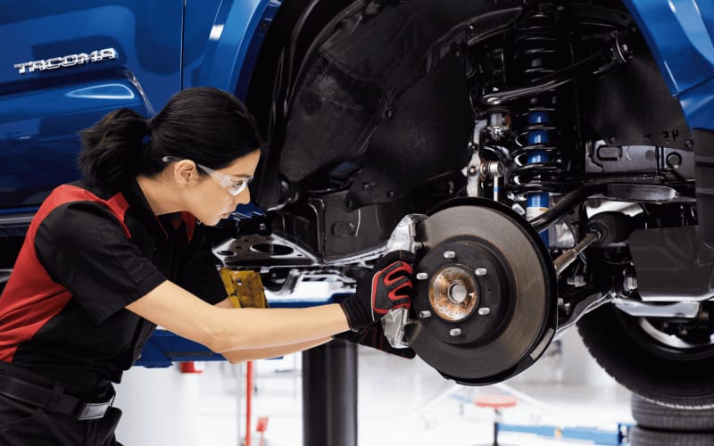 Technician inspecting the suspension of a Toyota on a lift