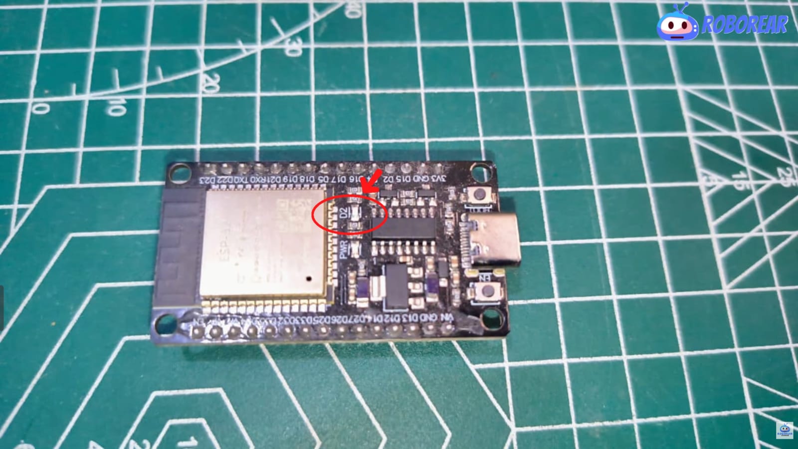 Close-up of an ESP32 development board on a green cutting mat with a red circle highlighting the onboard LED labeled D2, used for PlatformIO blink tests.