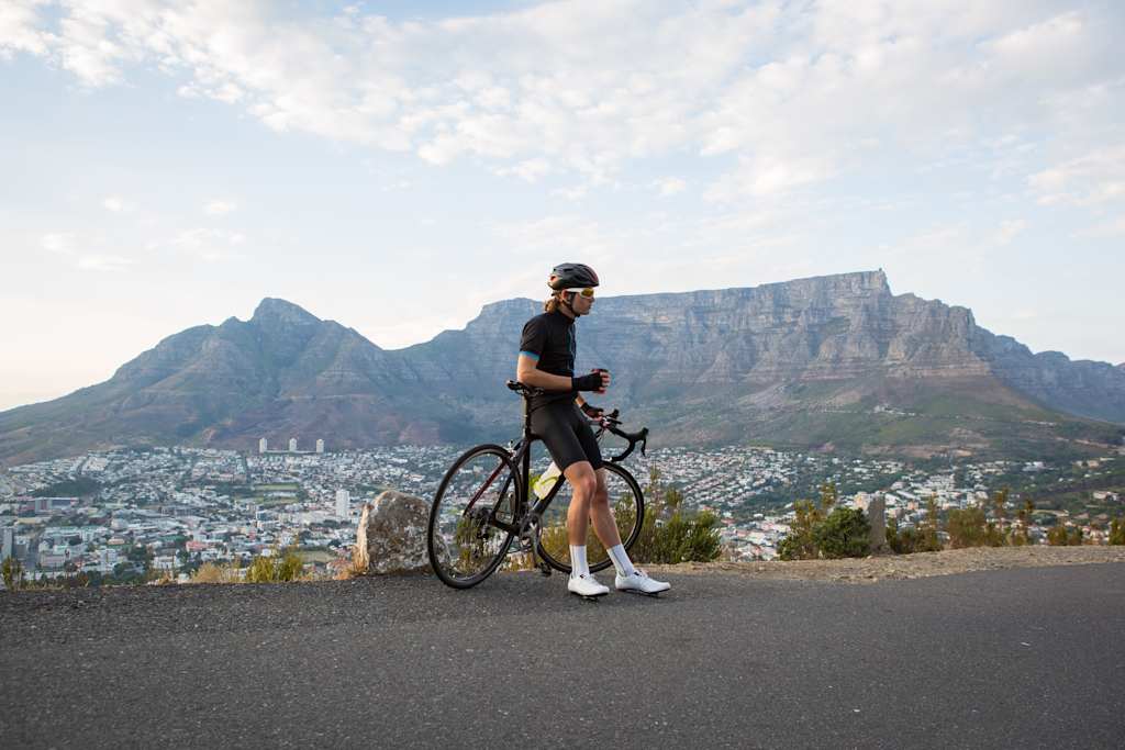 A male cyclist stops to admire the view over Cape Town and has a coffee break