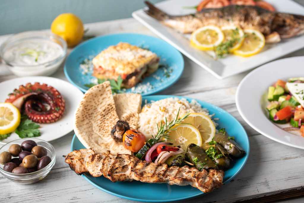 assorted popular greek plates on rustic wooden background
