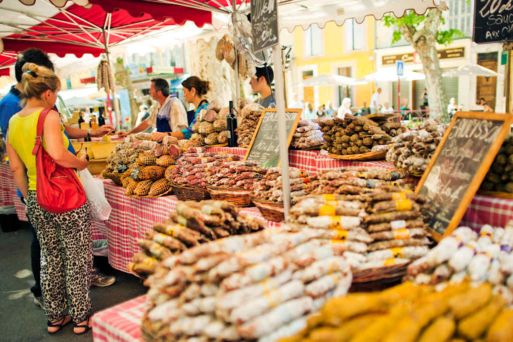 "Riez, France - July 14, 2012: Market vendors are selling sausages to buyers at a traditional market in Provence"