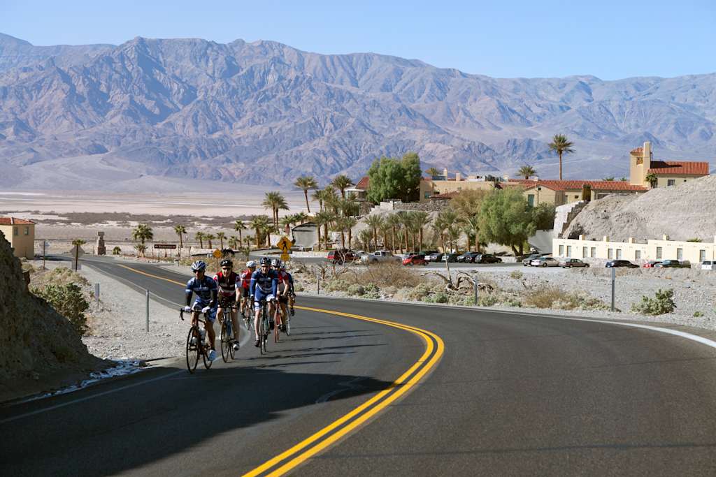 "Death Valley, USA - February 9th, 2012: 9 cyclers riding on clear sunny day on highway near Furnace Creek Inn and resort in Death Valley, California, USA."