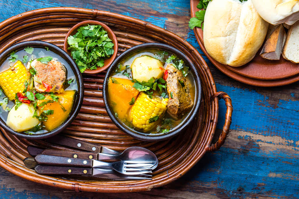 Latin American chilean food. Traditional chilean cazuela de cerdo with chuchoca. Pork soup with potatoes, pumpkin. corn served in clay bowl from Pomaire. Top view