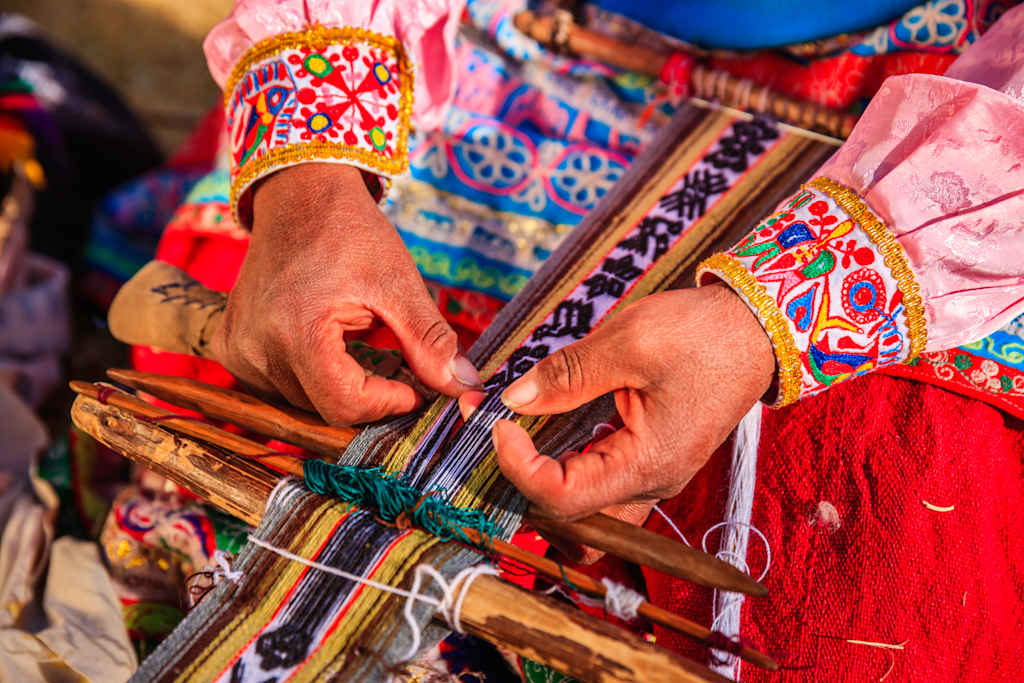 Vibrant, intricately patterned textiles and hands skillfully weaving them, showcasing the rich cultural heritage and craftsmanship.