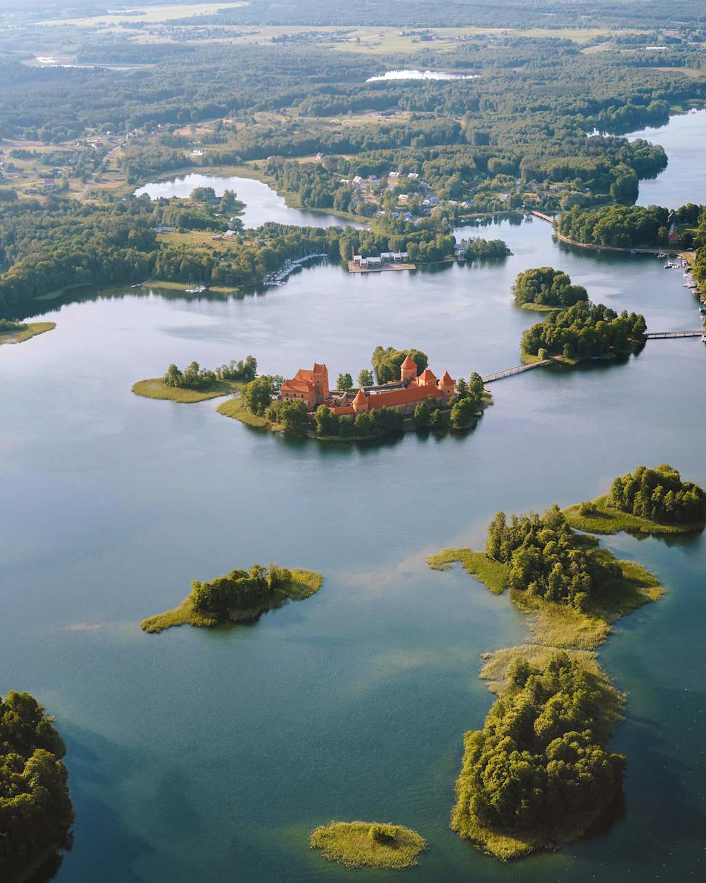 An aerial view of a picturesque lake surrounded by lush green islands, with a historic castle-like structure situated on one of the central islands.
