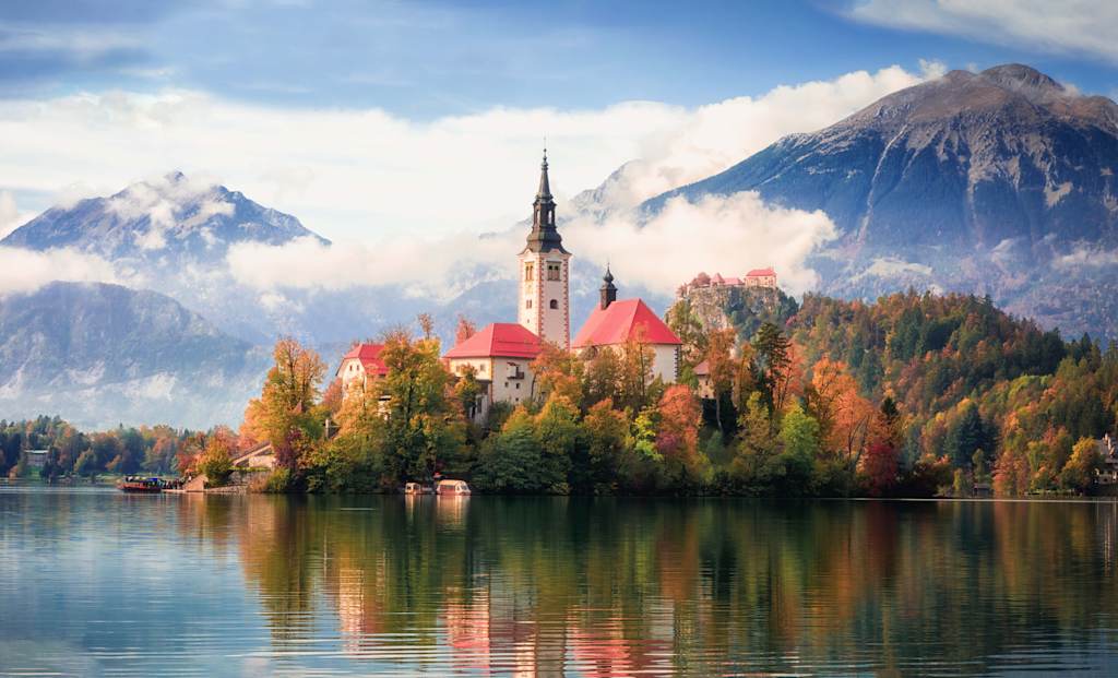 Famous alpine Bled lake in Slovenia, amazing autumn landscape. Scenic view of the lake, island with church, Bled castle, mountains and blue sky with clouds, outdoor travel background