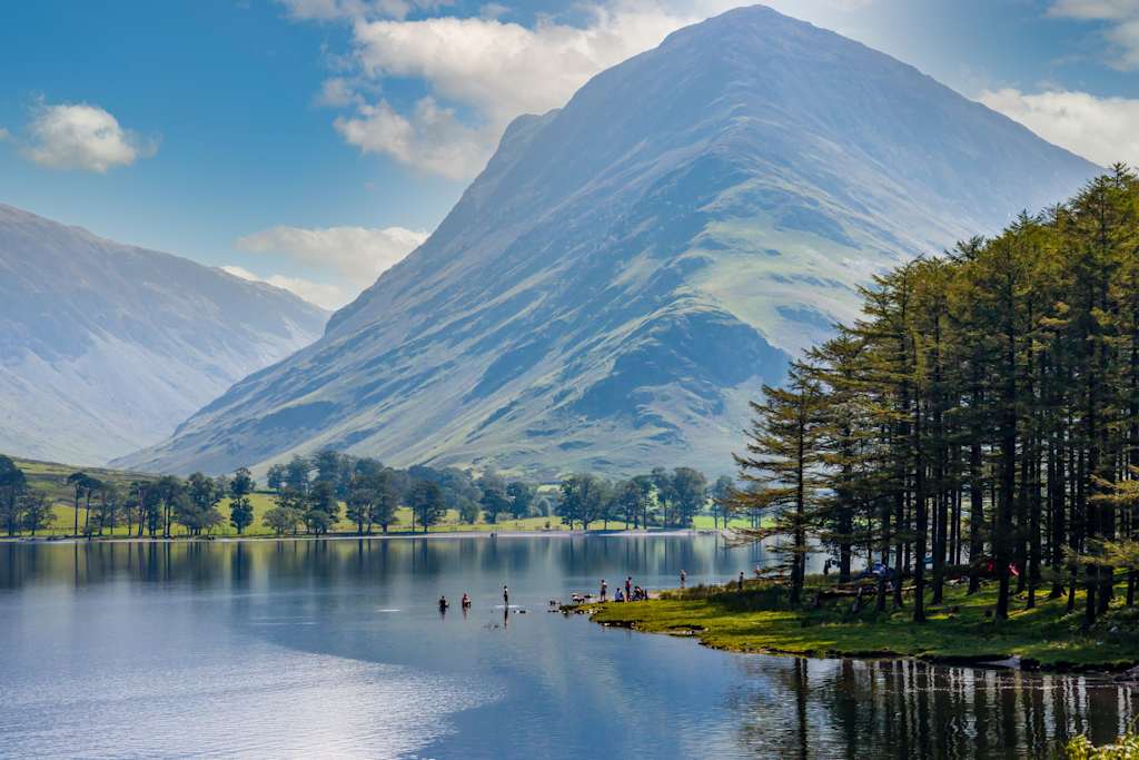 A serene lake surrounded by lush greenery and towering snow-capped mountains, creating a breathtaking natural landscape.
