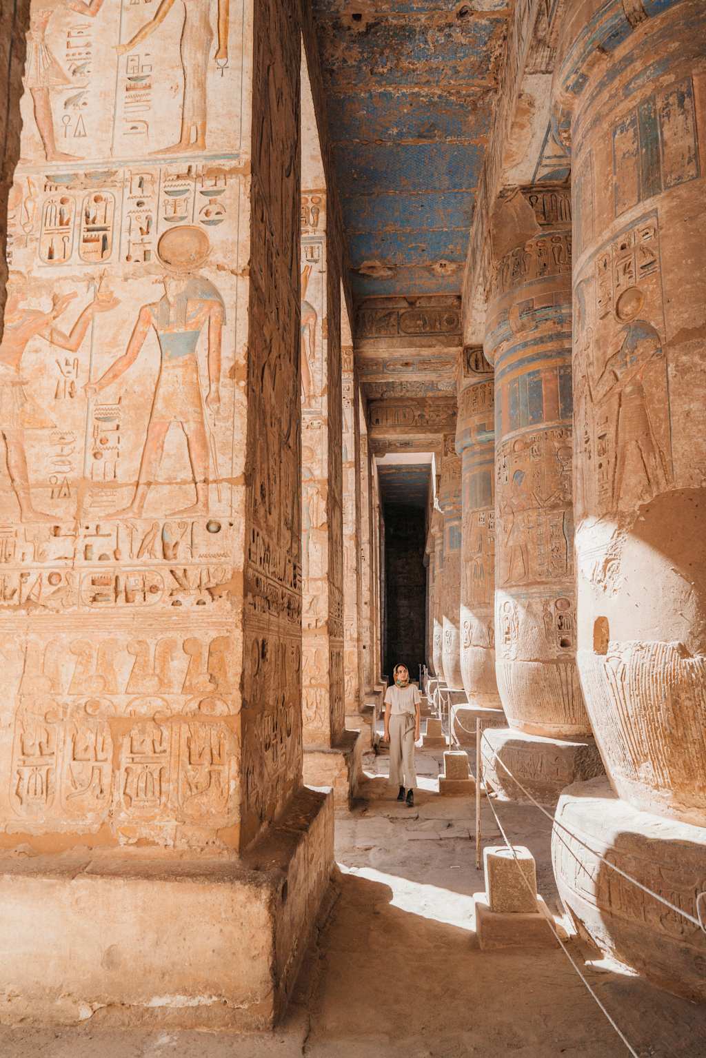 A grand, ancient Egyptian temple with intricate hieroglyphic carvings adorning the walls, leading to a dimly lit interior with massive stone statues and columns.