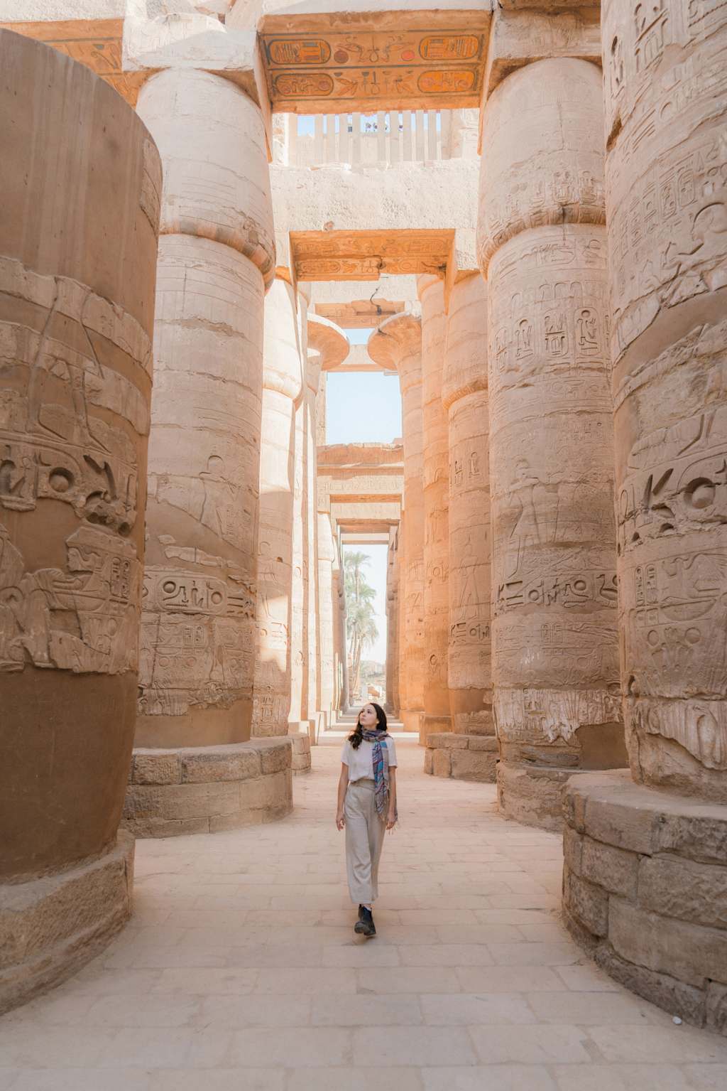 A person walks through a grand, ancient Egyptian temple with ornate columns and hieroglyphic-covered walls.