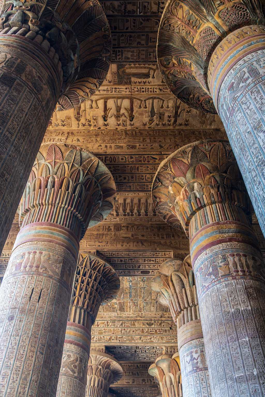 Ornate and intricately decorated columns with intricate carvings and patterns dominate the foreground, while the background features a complex, layered architectural structure with additional decorative elements.
