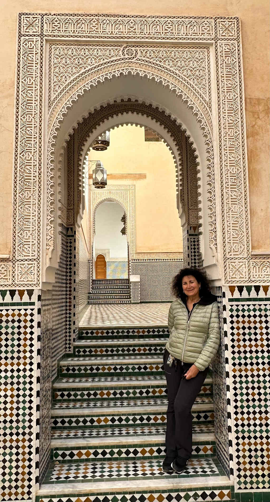 A vibrant array of colorful leather tanning vats and drying racks fills the foreground, surrounded by the traditional architecture of the historic Moroccan city in the background.