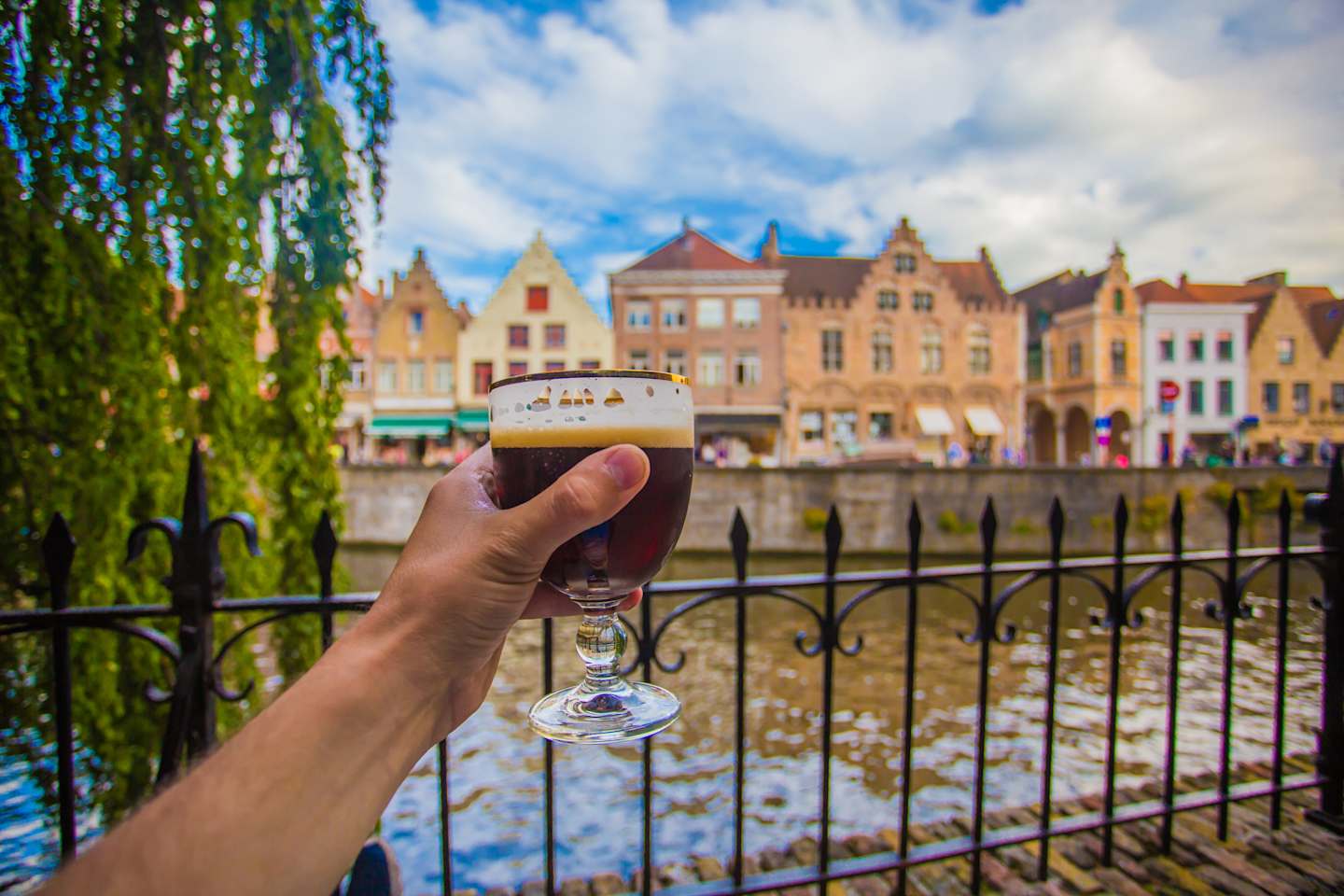 Hand with beer glass in Bruges, Belgium, with cityscape background