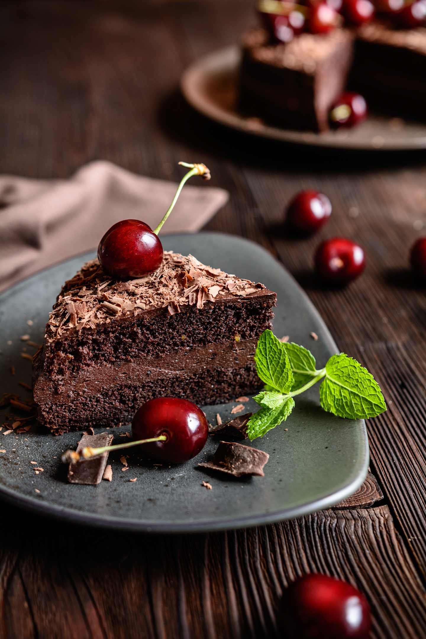 Chocolate cake filled with cocoa whipped cream and decorated with chocolate shavings and cherry